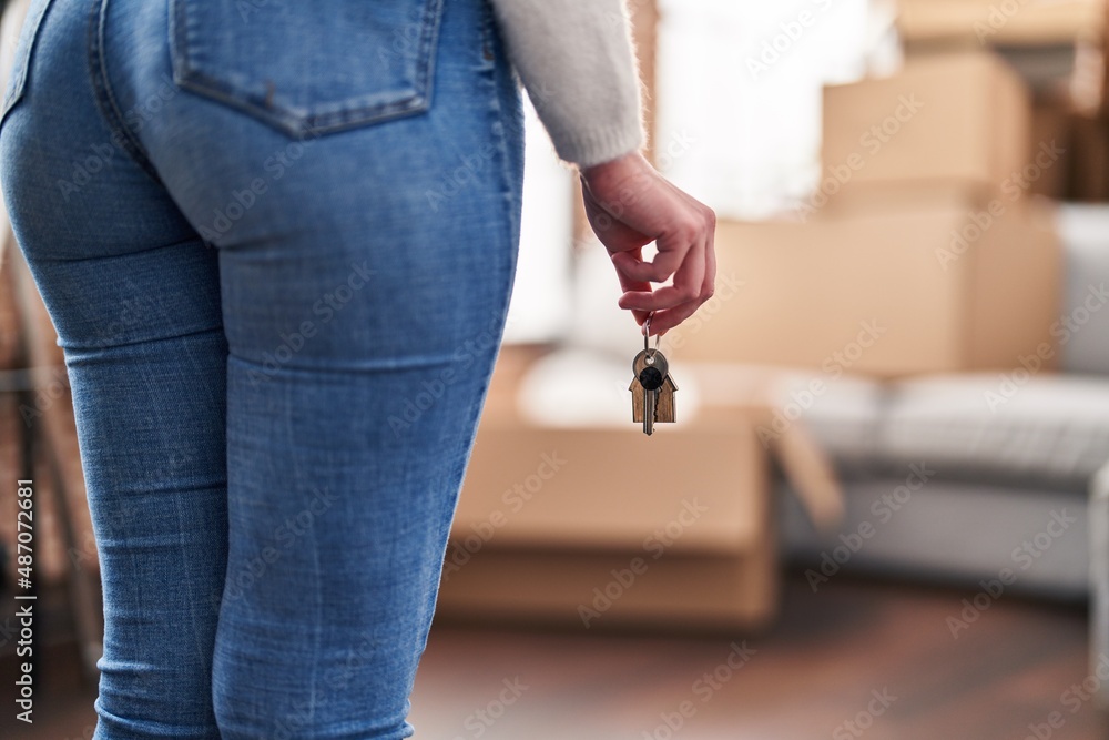 Obraz premium Young blonde woman holding key standing at new home