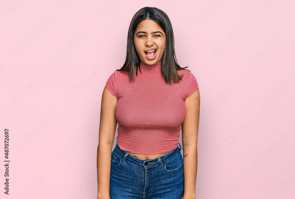 Young hispanic girl wearing casual t shirt winking looking at the camera with sexy expression, cheerful and happy face. Young hispanic girl wearing casual t shirt winking looking at the camera with sexy expression, cheerful and happy face.