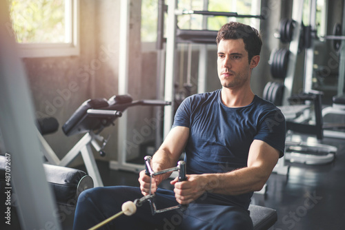 Wallpaper Mural Handsome man lowering weight of fitness machine and working out in the fitness gym Torontodigital.ca