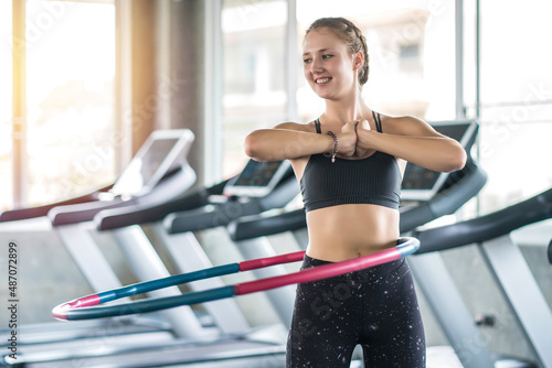 Young woman doing hula hoop during an exercise class in fitness gym. Healthy sports lifestyle, Fitness, Healthy concept
