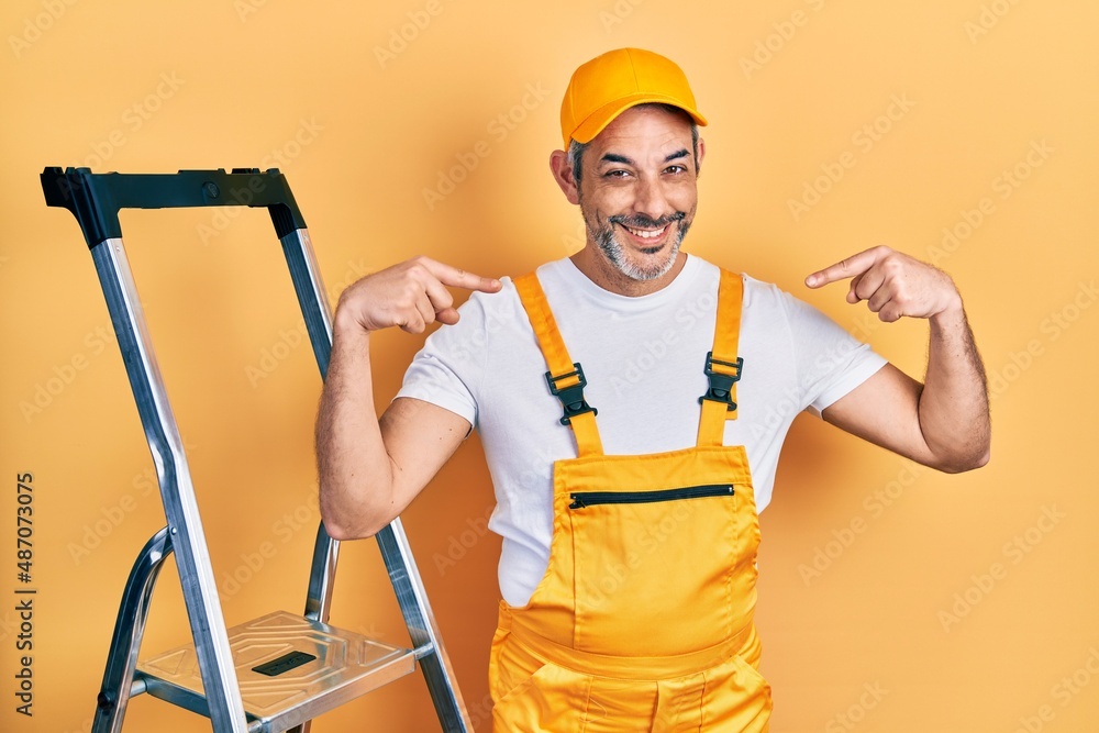 Handsome middle age man with grey hair holding ladder looking confident with smile on face, pointing oneself with fingers proud and happy. Handsome middle age man with grey hair holding ladder looking confident with smile on face, pointing oneself with fingers proud and happy.