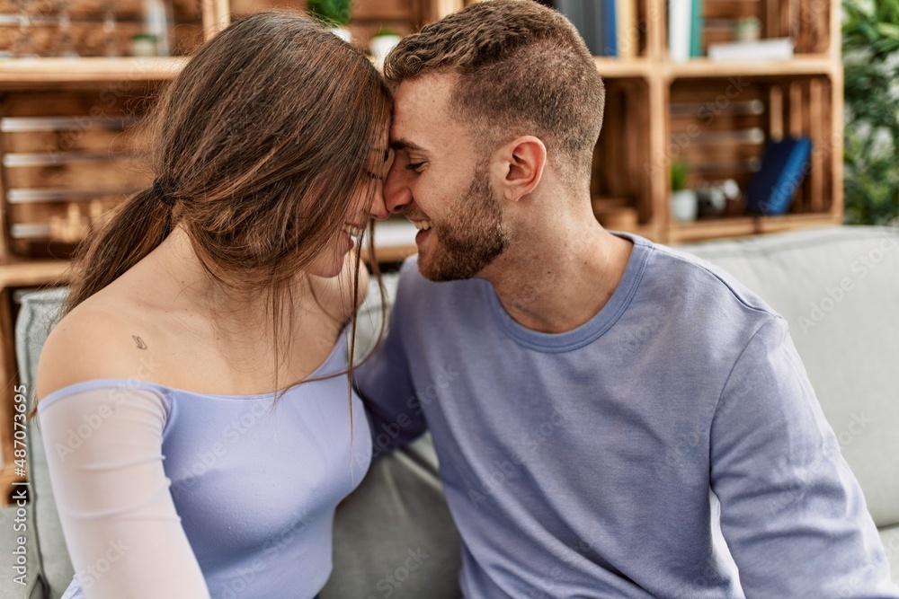 Young caucasian couple sitting on the sofa hugging at home. Young caucasian couple sitting on the sofa hugging at home.