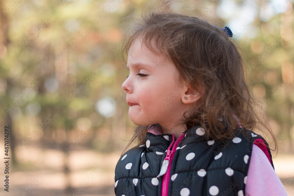 Beautiful little girl in a polka dot vest on a walk in the forest Beautiful little girl in a polka dot vest on a walk in the forest