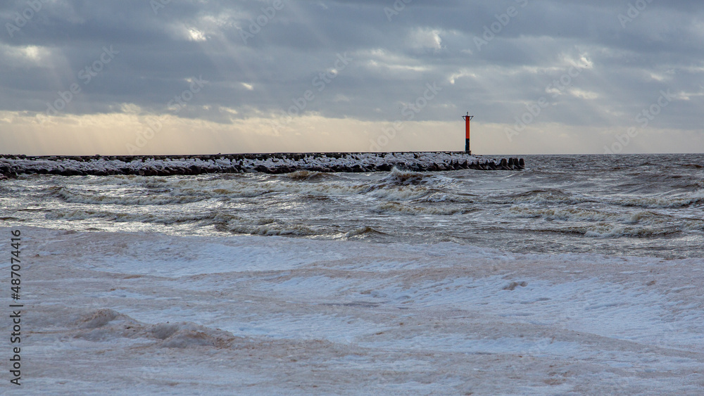 Lighthouse under dramatic sky at Skulte port in winter afternoon in Latvia