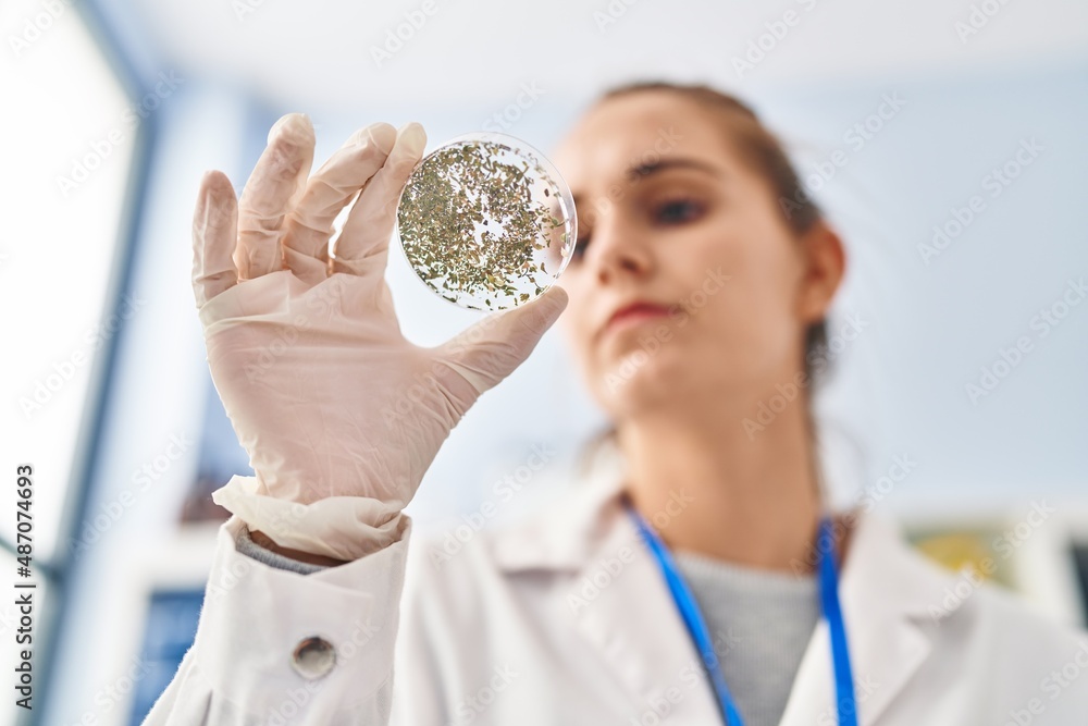 Young blonde woman wearing scientist uniform looking sample at laboratory Young blonde woman wearing scientist uniform looking sample at laboratory