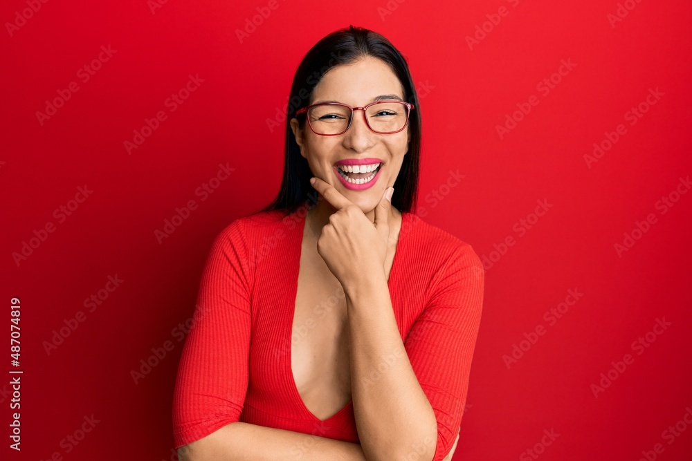 Young latin woman wearing casual clothes and glasses looking confident at the camera smiling with crossed arms and hand raised on chin. thinking positive. Young latin woman wearing casual clothes and glasses looking confident at the camera smiling with crossed arms and hand raised on chin. thinking positive.