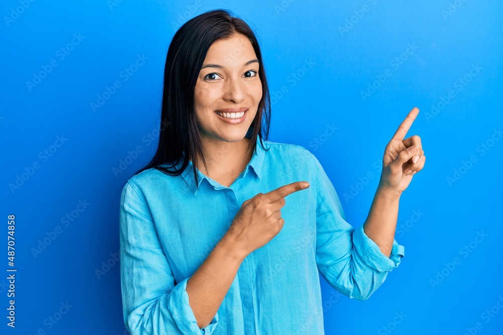 Young latin woman wearing casual clothes smiling and looking at the camera pointing with two hands and fingers to the side. Young latin woman wearing casual clothes smiling and looking at the camera pointing with two hands and fingers to the side.