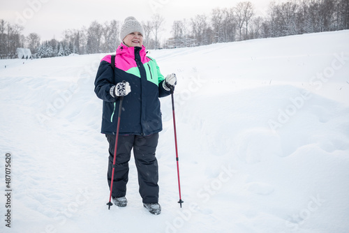 An elderly woman is engaged in Nordic walking in a winter city park. © Zuev Ali