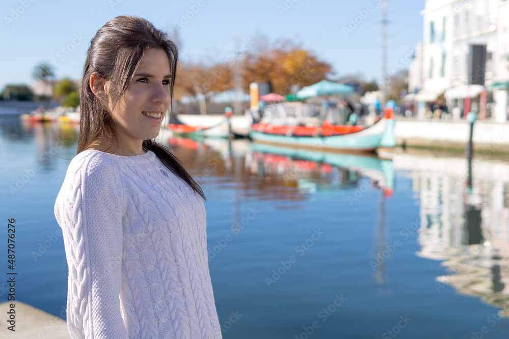 Young female tourist in close-up in front of a canal with boats in Aveiro, Portugal.