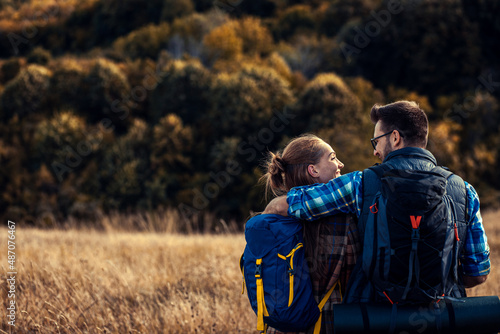 Rear view of couple with backpacks hiking together in nature on autumn day. © Zoran Zeremski