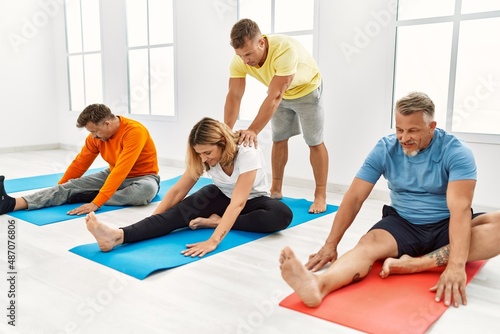 Group of middle age people training with personal trainer at sport center.