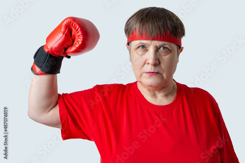 Elderly woman boxer in red on a white background. © Zuev Ali