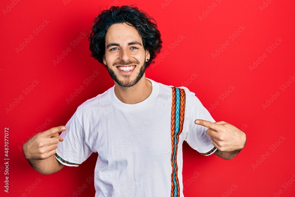 Handsome hispanic man wearing casual white t shirt looking confident with smile on face, pointing oneself with fingers proud and happy. Handsome hispanic man wearing casual white t shirt looking confident with smile on face, pointing oneself with fingers proud and happy.