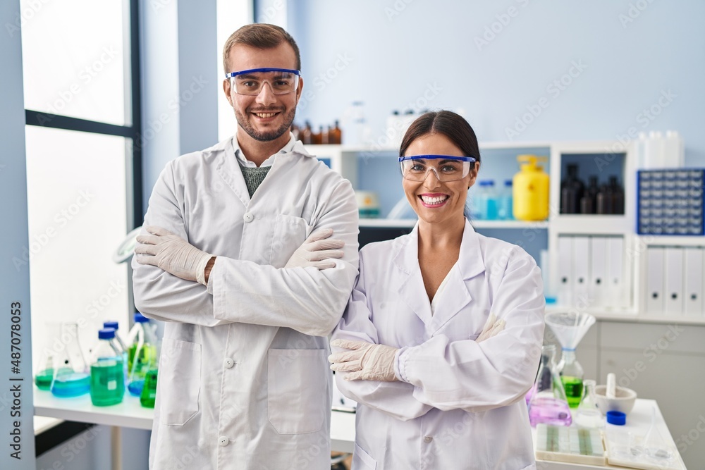 Man and woman scientist partners standing with arms crossed gesture at laboratory Man and woman scientist partners standing with arms crossed gesture at laboratory