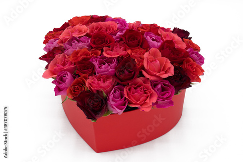 Heart of colorful red roses in a box on white background
