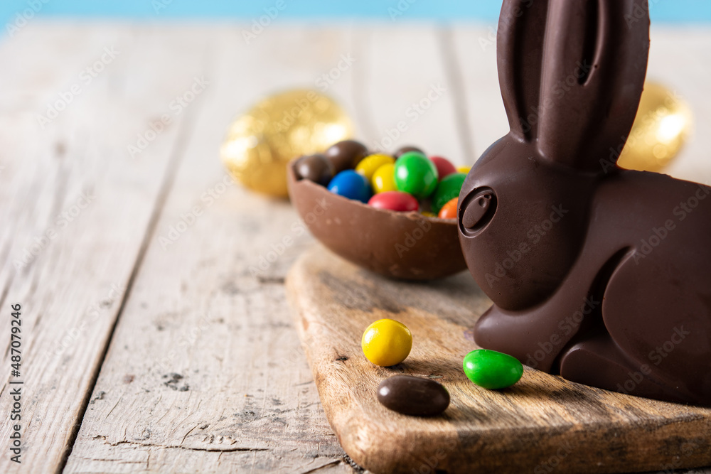 Easter chocolate bunny and colorful eggs on wooden table.Copy space