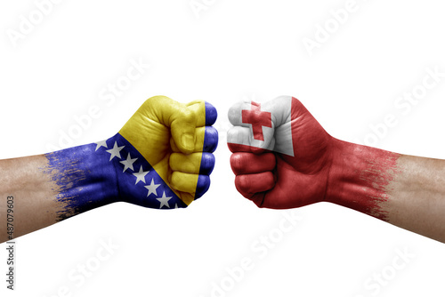 Two hands punch to each others on white background. Country flags painted fists, conflict crisis concept between bosnia and tonga