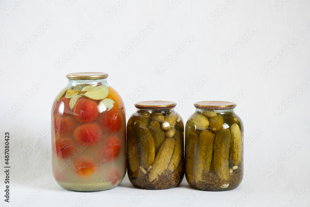 canned homemade tomatoes and cucumbers in jars on a white background close up canned homemade tomatoes and cucumbers in jars on a white background close up