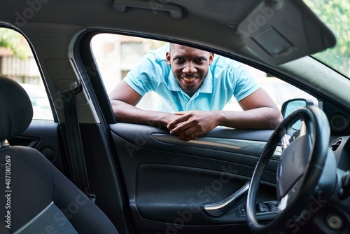 Young african american man smiling confident looking car leaning on door at street