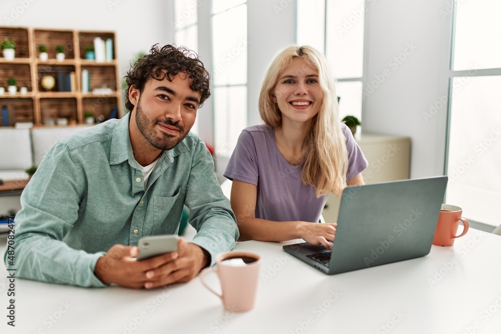 Young couple using laptop and smartphone drinking coffee at home. Young couple using laptop and smartphone drinking coffee at home.