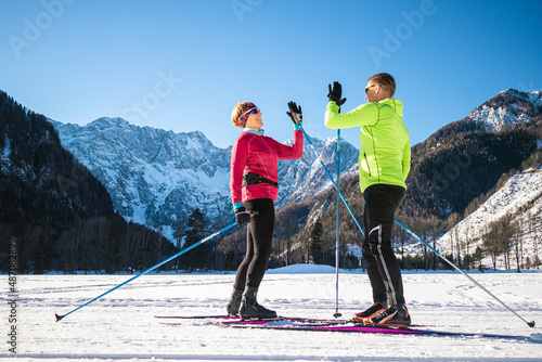 Mature couple, cross country skiers, standing on a ski trail and looking at incredible snow mountain peaks. photo