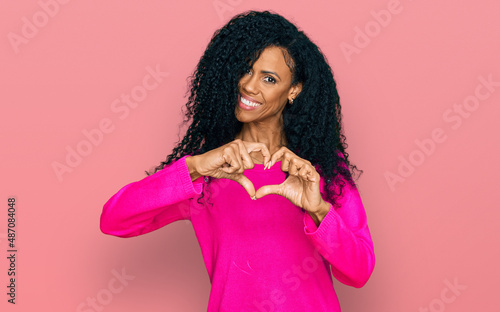 Middle age african american woman wearing casual clothes smiling in love doing heart symbol shape with hands. romantic concept.