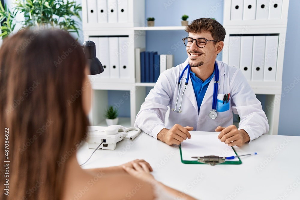 Young doctor with client at medical clinic looking away to side with smile on face, natural expression. laughing confident. Young doctor with client at medical clinic looking away to side with smile on face, natural expression. laughing confident.