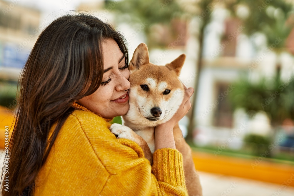 Beautiful young woman kissing and hugging shiba inu dog at park Beautiful young woman kissing and hugging shiba inu dog at park