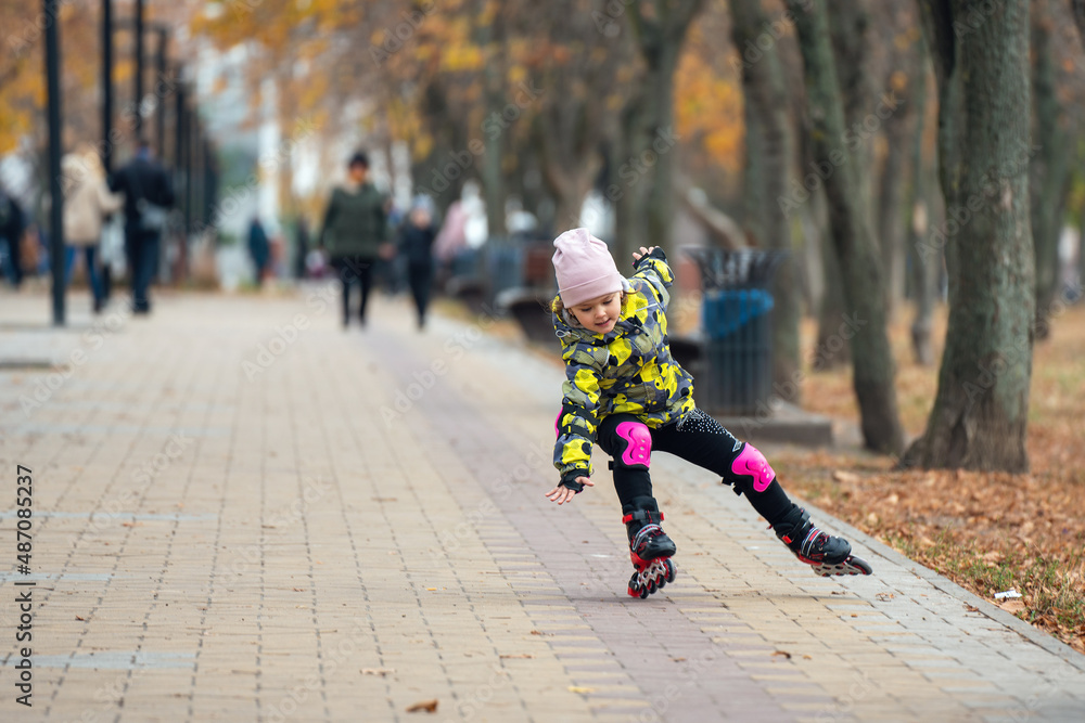 Cute little girl learns to roller skate. A child on roller skates falls