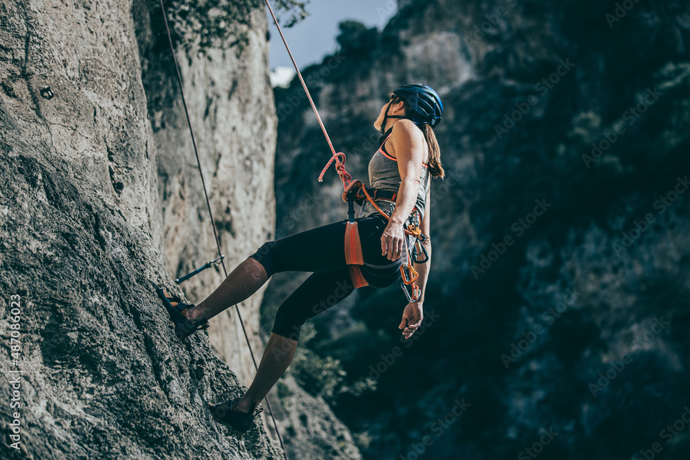 Woman descending a cliff after a hard climb route - obrazy, fototapety, plakaty 