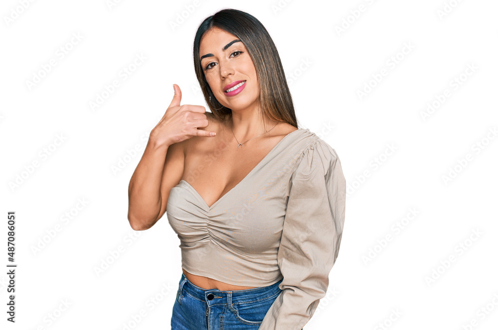 Young hispanic woman wearing casual clothes smiling doing phone gesture with hand and fingers like talking on the telephone. communicating concepts. Young hispanic woman wearing casual clothes smiling doing phone gesture with hand and fingers like talking on the telephone. communicating concepts.
