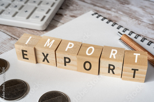 貿易のイメージ｜「IMPORT」「EXPORT」と書かれた積み木、コイン、計算機、ペン、ノート
