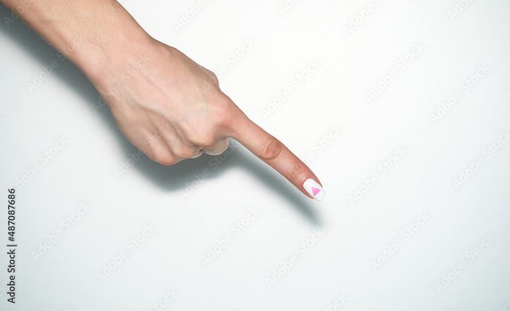 Pointing gesture. Female hand shows index finger with rose triangle manicure. Symbol of lesbian, gay, bisexual, transgender and queer pride isolated on white background. Pointing gesture. Female hand shows index finger with rose triangle manicure. Symbol of lesbian, gay, bisexual, transgender and queer pride isolated on white background.