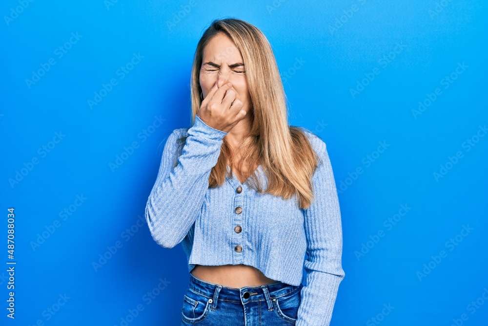Young caucasian woman wearing casual clothes smelling something stinky and disgusting, intolerable smell, holding breath with fingers on nose. bad smell Young caucasian woman wearing casual clothes smelling something stinky and disgusting, intolerable smell, holding breath with fingers on nose. bad smell