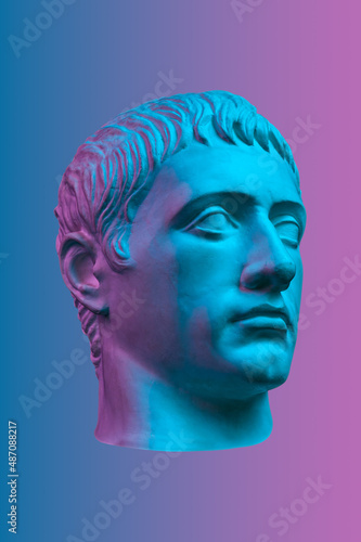 Blue purple gypsum copy of ancient statue of Germanicus Julius Caesar head for artists isolated on color background. Renaissance epoch. Plaster sculpture of man face.Template for art design