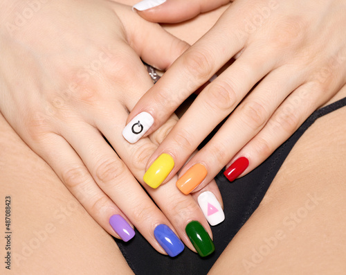 Woman hands with LGBT rainbow flag and rose triangle manicure covering pubis. Symbol of lesbian  gay  bisexual  transgender and queer pride.