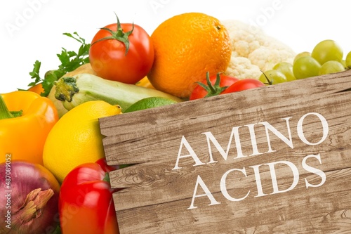 Wooden board with text AMINO ACIDS among different products and vegetables