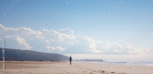 Backpacker female sitting on the Patara sand dunes beach enjoying the windy Mediterranean Sea during Lycian Way trekking walk. Famous Likya Yolu Turkish route. Active people vacation concept image