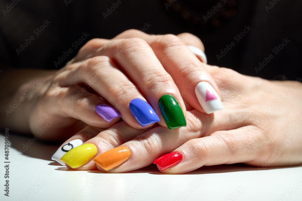 Hands with LGBT rainbow flag and rose triangle manicure. Symbol of lesbian, gay, bisexual, transgender and queer pride. Hands with LGBT rainbow flag and rose triangle manicure. Symbol of lesbian, gay, bisexual, transgender and queer pride.