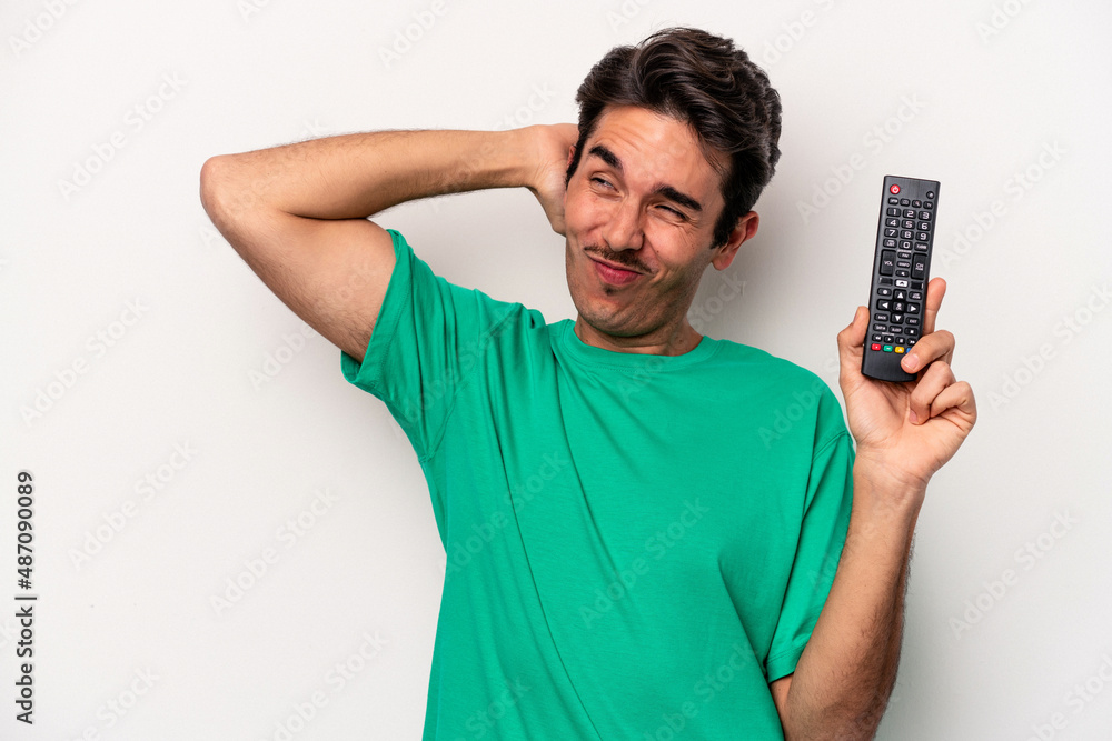 Young caucasian man holding a tv remote isolated on white background touching back of head, thinking and making a choice. Young caucasian man holding a tv remote isolated on white background touching back of head, thinking and making a choice.