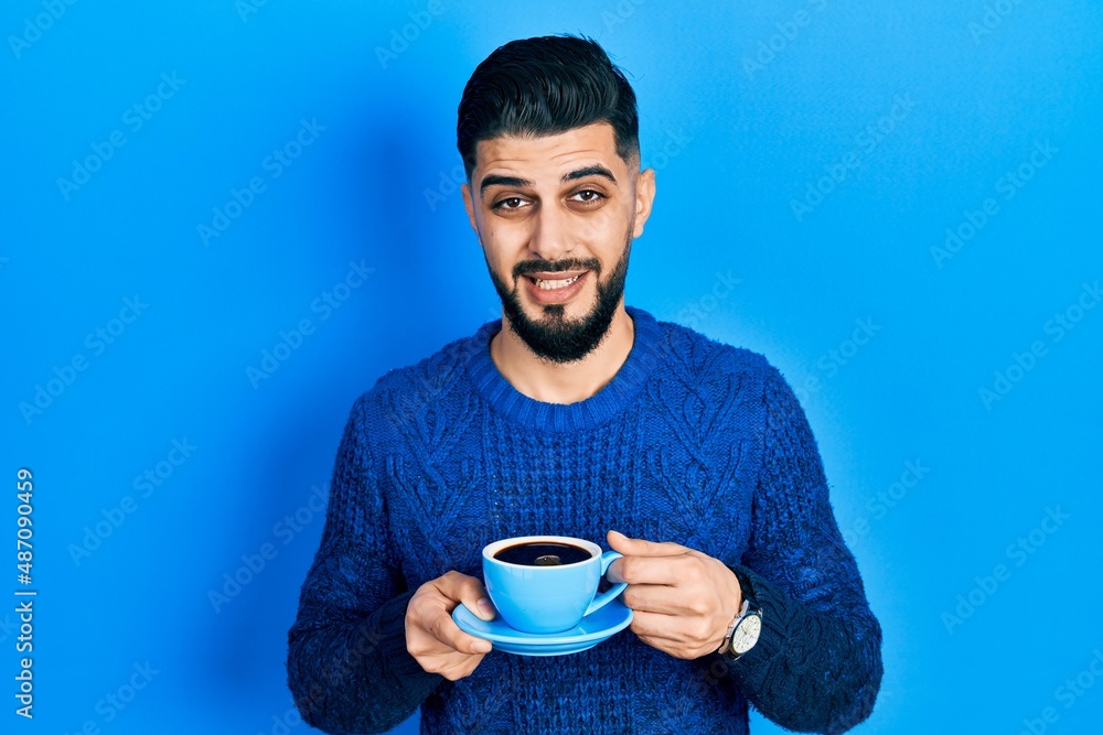 Handsome man with beard drinking a cup of coffee clueless and confused expression. doubt concept. Handsome man with beard drinking a cup of coffee clueless and confused expression. doubt concept.