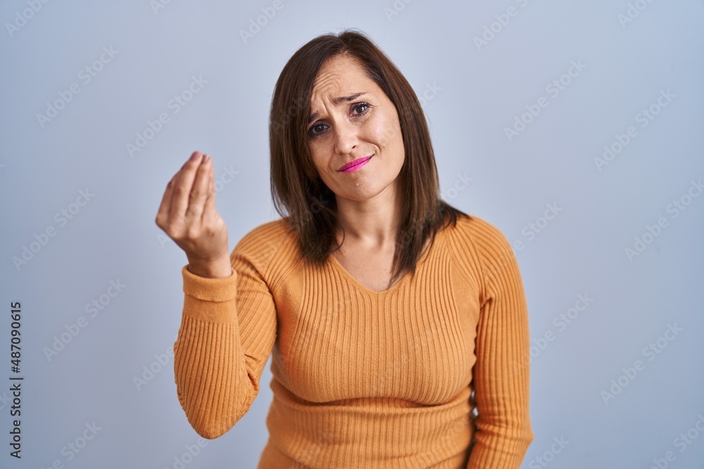 Middle age brunette woman standing wearing orange sweater doing italian gesture with hand and fingers confident expression Middle age brunette woman standing wearing orange sweater doing italian gesture with hand and fingers confident expression