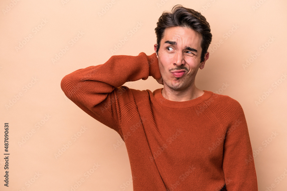Young caucasian man isolated on beige background touching back of head, thinking and making a choice. Young caucasian man isolated on beige background touching back of head, thinking and making a choice.