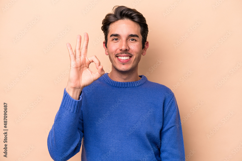 Young caucasian man isolated on beige background cheerful and confident showing ok gesture. Young caucasian man isolated on beige background cheerful and confident showing ok gesture.