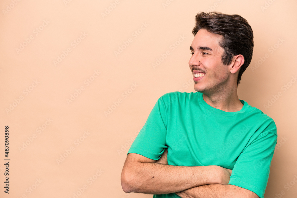 Young caucasian man isolated on beige background smiling confident with crossed arms. Young caucasian man isolated on beige background smiling confident with crossed arms.