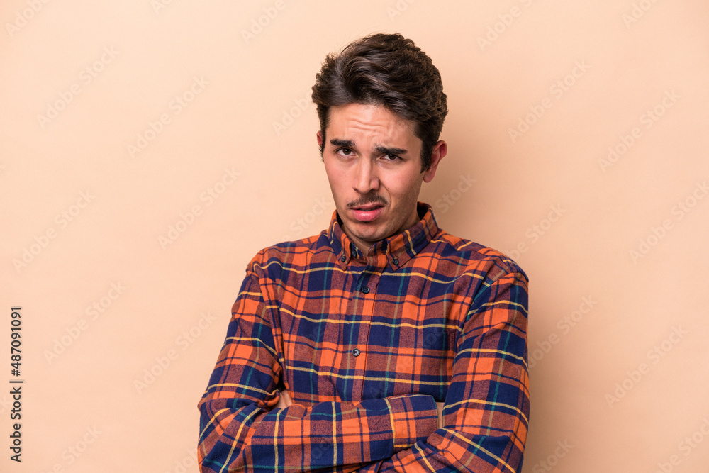 Young caucasian man isolated on beige background who is bored, fatigued and need a relax day. Young caucasian man isolated on beige background who is bored, fatigued and need a relax day.