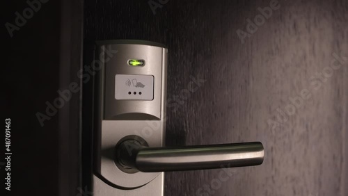 Close up of female hand using keyless entry card for opening door at hotel room. Private pass and security system concept.