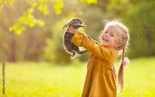 The girl is holding a little rabbit in her arms and laughing