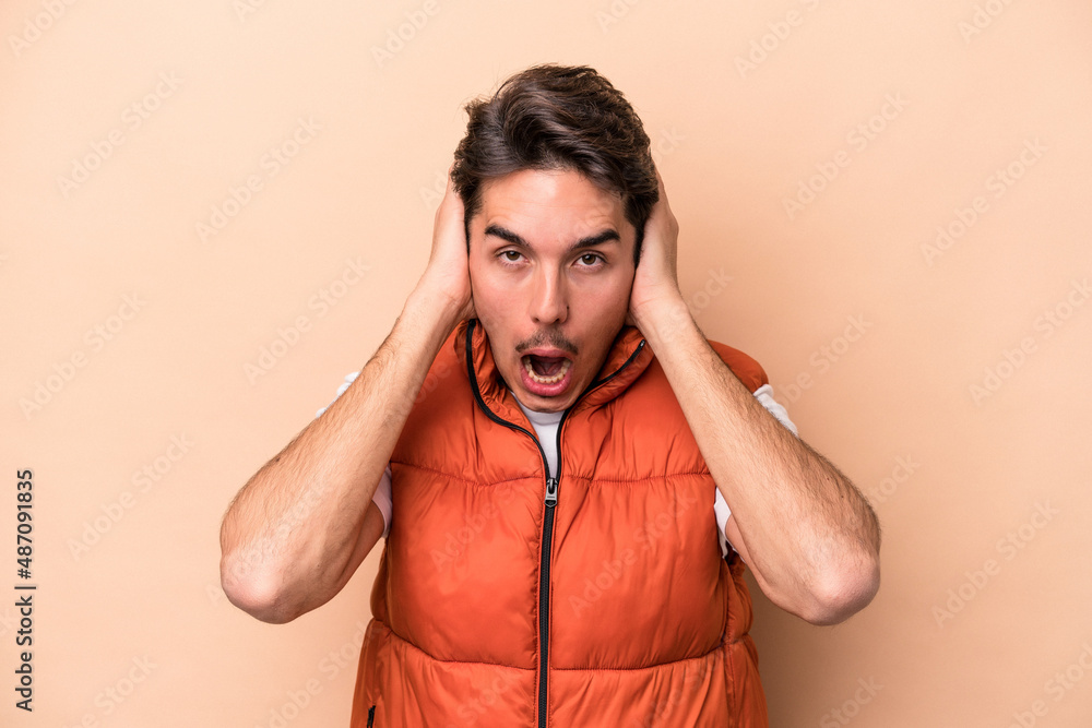 Young caucasian man isolated on beige background screaming, very excited, passionate, satisfied with something. Young caucasian man isolated on beige background screaming, very excited, passionate, satisfied with something.
