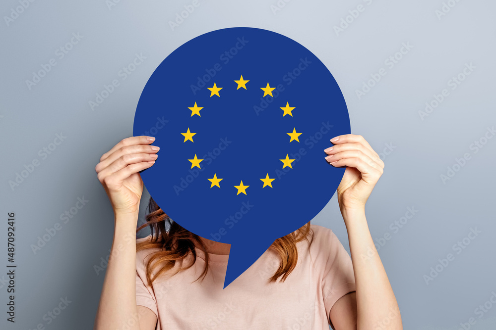 Obraz na płótnie woman holds blank white speech bubble with european union flag isolated over grey studio background. News information channel concept w salonie